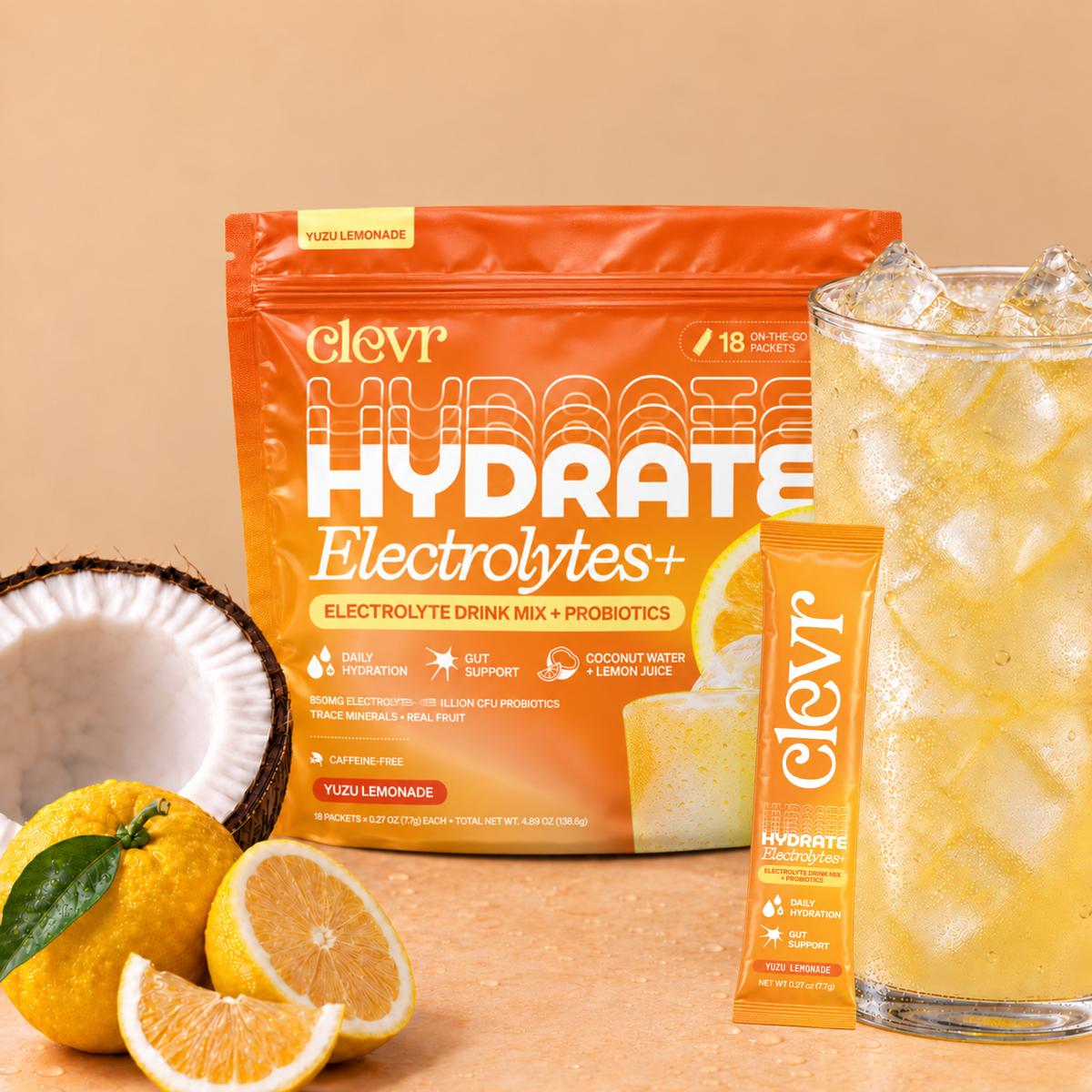 Clevr Hydrate Electrolytes+ pouch in Yuzu Lemonade flavor, shown with a single stick packet, a glass of iced yellow drink, and lemon/coconut props on a warm beige background.