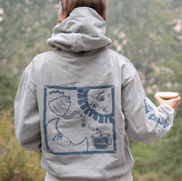 Person wearing hoodie and showing back image of sun, moon, and Clevr being poured into a cup