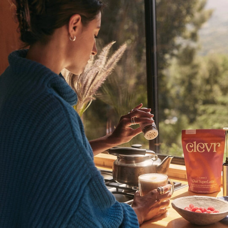 Person sprinkling Clevr Latte Dust onto a Clevr SuperLatte in a kitchen by a window