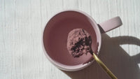 Person making Clevr SuperLatte by adding powder to a mug, pouring water in, and frothing it