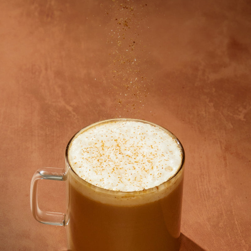 Clevr Latte Dust sprinkling onto a Clevr SuperLatte in a mug